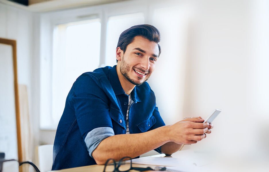 ein Mann, der an einem Schreibtisch sitzt und eine Zelle benutzt