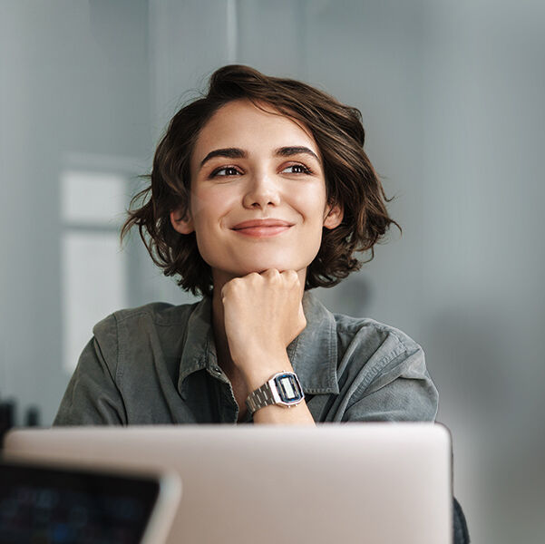 eine Frau sitzt lächelnd vor einem Laptop